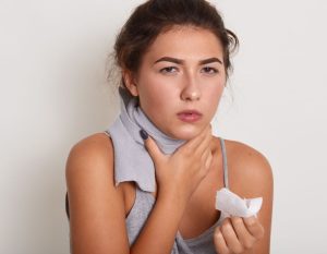 Image of sick young dark haired woman posing isolated over white studio background, unhealthy lady touches neck, feels discomfort, has painful feelings, hard to swallow, has sore throat or catch cold.